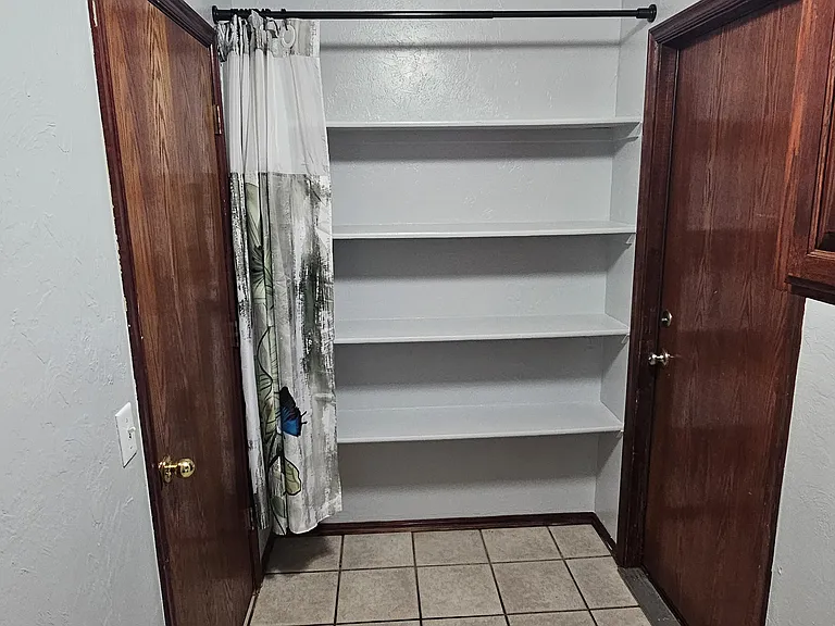 Pantry shelves in laundry room area with garage access on right and kitchen entry on left