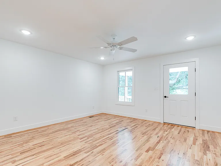 Primary bedroom featuring hardwoods, recessed lights, ceiling fan, walk-in closet, private bathroom with walk-in shower and double vanity, and access to covered balcony overlooking backyard