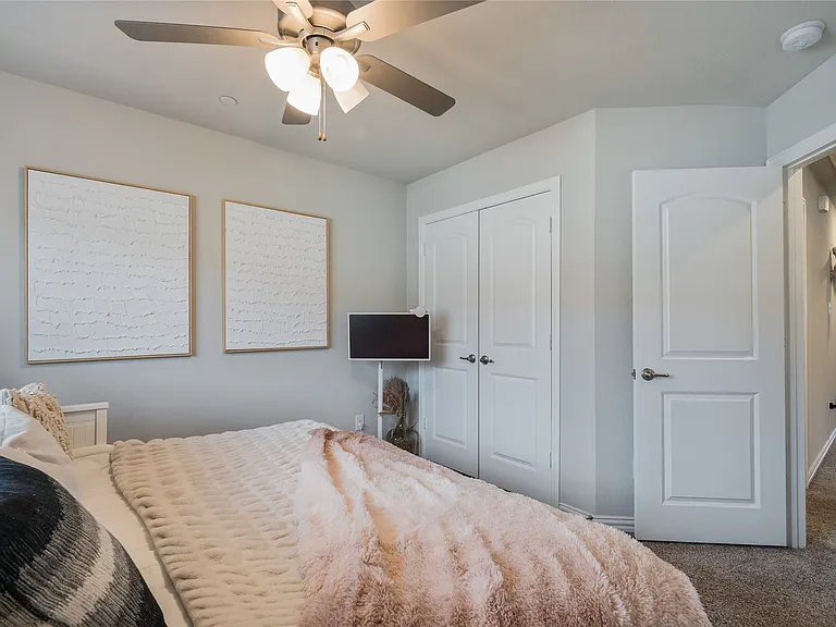 Carpeted room featuring a ceiling fan with integrated lighting, a paneled door, and light gray wall paint