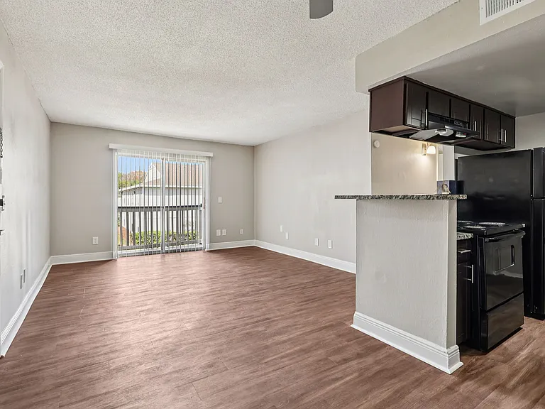 Spacious living area with wood-style flooring and an open kitchen with breakfast bar.