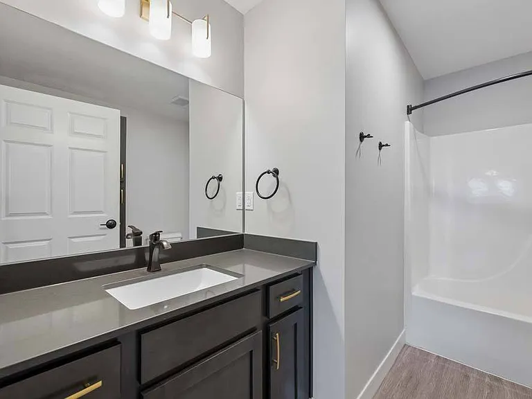 Refresh and recharge in a thoughtfully finished bathroom featuring a spacious vanity and a sleek tub-and-shower combination.