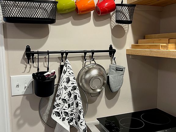 Kitchen has hanging bars, butcher block shelves, and a double burner.