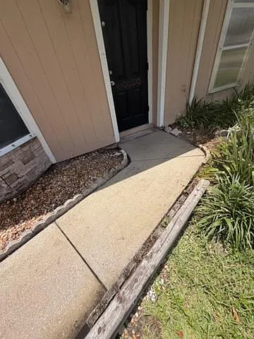 Covered front entry with a concrete walkway, landscaped edging, and a secure door for easy everyday access.
