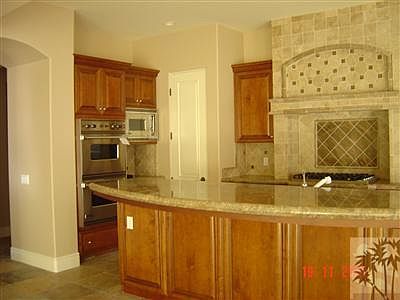 Kitchen view showing extensive tile decor and granite slab counters with upgraded cabinetry.