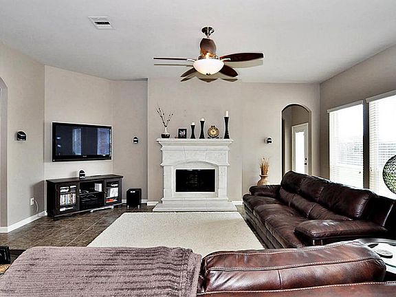 Another view of the living room featuring the cast stone fireplace and upgraded ceiling fan.