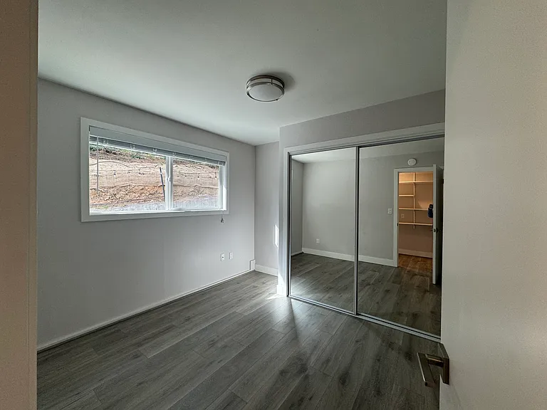 2nd Bedroom with mirrored closet doors, natural light, and a modern finish.
