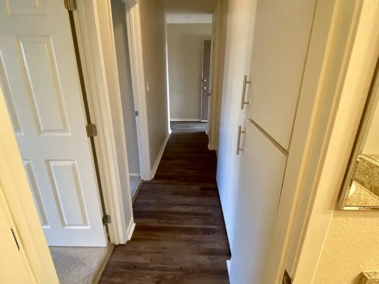 Looking from bathroom down bedroom hallway with built-in cabinets at Villa Pacific Apartments in Oceanside, California.