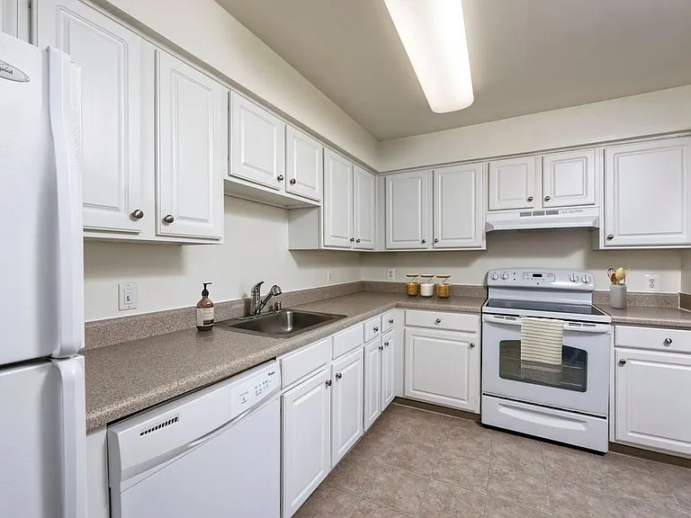 Classic Woods kitchen with white appliances, white cabinetry, grey laminate countertops, and tile flooring