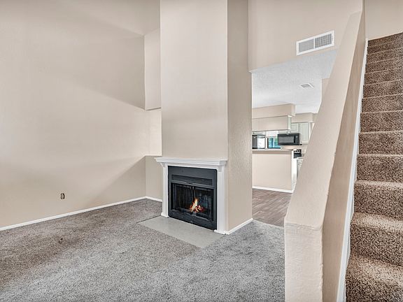Cozy living room with plush carpeting and fireplace_ideal for modern townhome/apartment living in Grand Prairie.