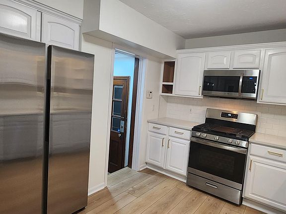 Updated kitchen featuring a premium Samsung stainless steel refrigerator, paired with stainless range and microwave with durable top tier oak-style flooring. Clean, bright, and move-in ready.