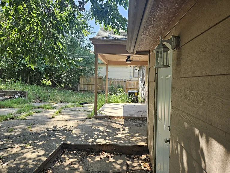 backyard looking toward covered patio with ceiling fan