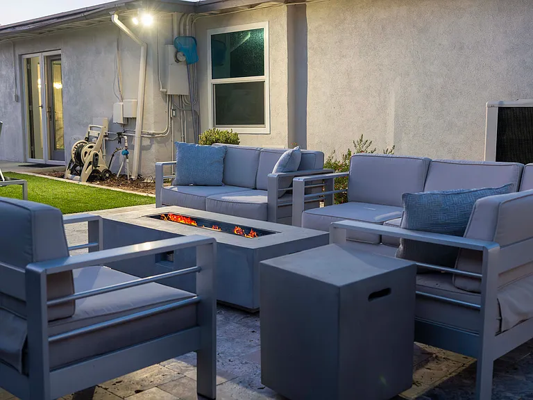 Outdoor patio with fire pit, seating area, and shade umbrella