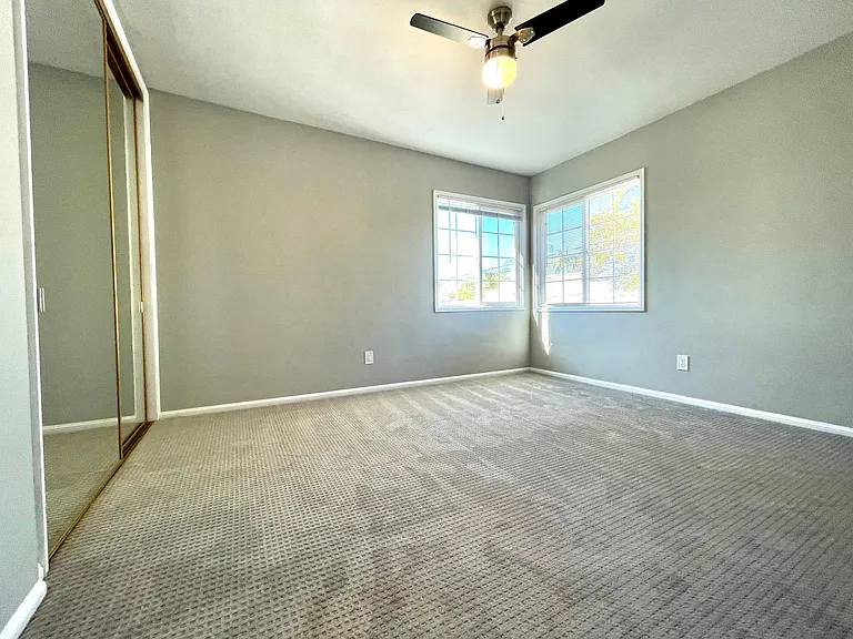 Bedroom with corner windows and ceiling fan for great natural light and breezes.