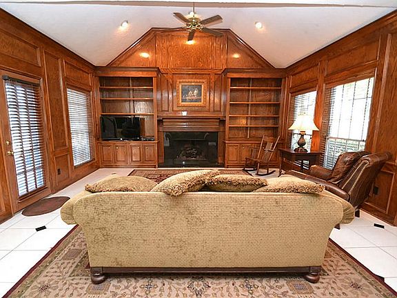 Family room featuring tile floors, coffered ceilings, recessed lighting, ceiling fan, blocked paneling, fireplace with gas logs, built-in bookshelves and French door to the patio area.