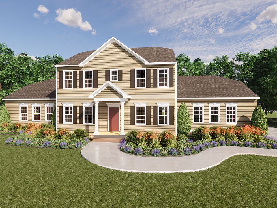 Two-story tan house with white trim in Belleair, surrounded by trees, flowers, and a curved driveway