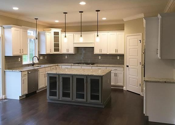 Gorgeous kitchen with white cabinetry, gray island, beautiful granite and wood floors.