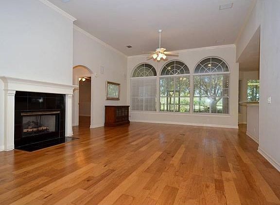 The living room has a gas log fireplace which can also be viewed from the formal dining, kitchen and breakfast nook. The piece of furniture in the back contains the equipment associated with the speakers found in the house. The triple arched windows provi