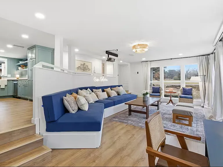 Living room with TV projector and 80" screen and working desk. Couch with drawer makes out into three twin beds.