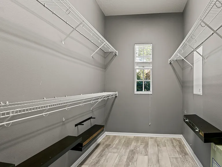 Primary bedroom walk-in closet with custom shoe racks