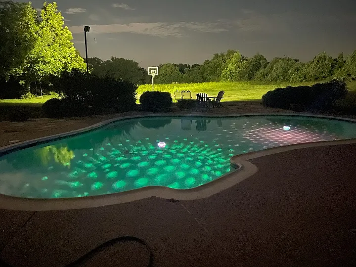 Pool with lighted basketball court in the background