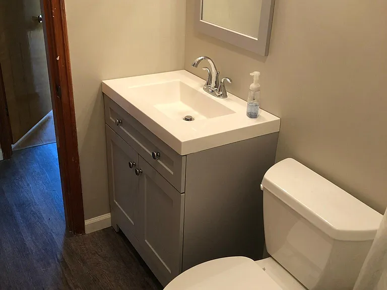 Main bath with new flooring, vanity, sink and mirror.