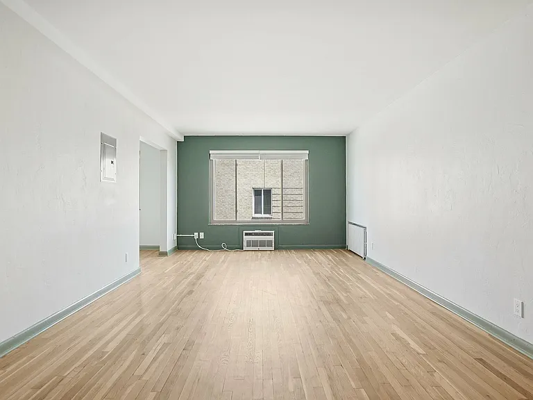 Bright and spacious living room with elegant wooden flooring and a large window offering natural light.