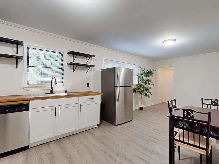 Eat-in kitchen with stainless appliances, generous counter space, open shelving, and room for a dining table.