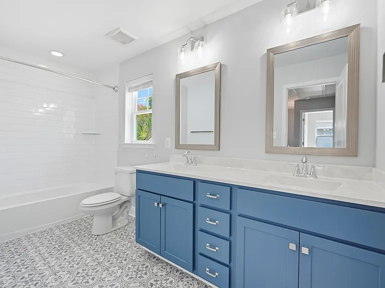 Upstairs bathroom with large double vanity, tub, and custom tile.