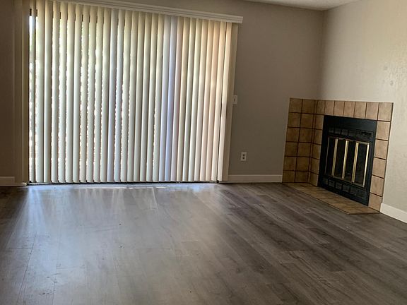 Large living room space with wood-burning fireplace and access to private patio