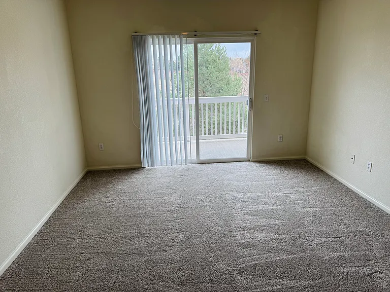 Primary bedroom with ceiling fan and access to the back balcony overlooking open space