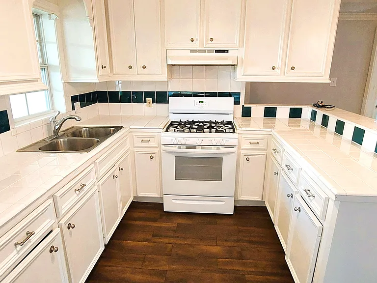 Kitchen:Custom white cabinets, with Gas stove, Fridge and garbage disposal and double sinks.