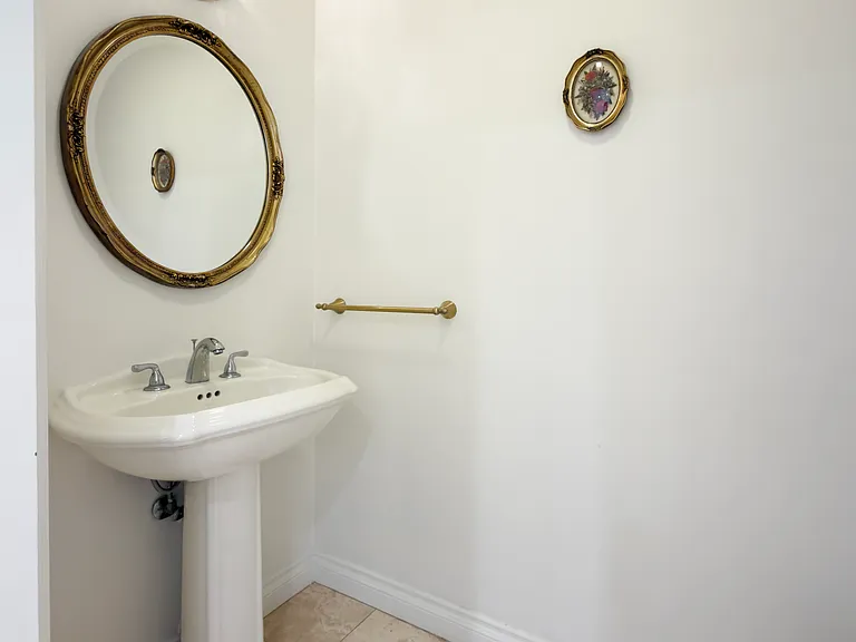 Charming powder room with a pedestal sink and round mirror adds classic style to this Beverly Hills luxury rental at 1094 Garden Lane, a 90210 home for rent.