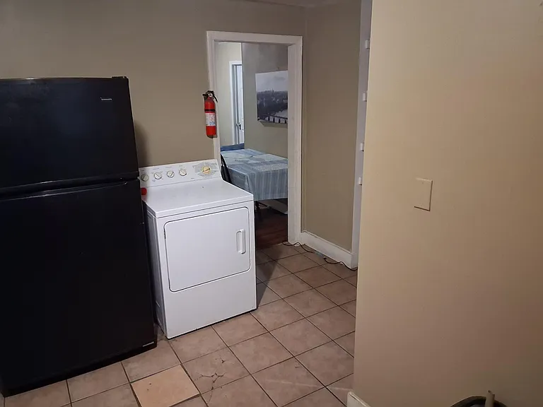 Convenient in-home laundry area with full-size washer and dryer, set on durable tile flooring with easy access to nearby room