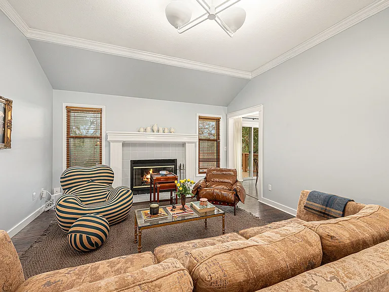 A spacious, stylish lounge with a fireplace, comfy sofa, and unique chairs_ideal for settling in and enjoying the cozy ambiance.