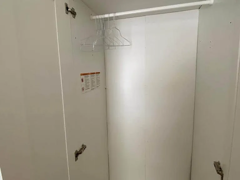 Open closet for storing clothes, with hangers and space for belongings.