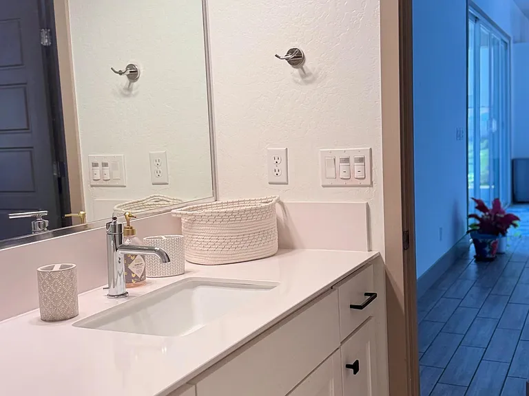 Clean single-sink vanity with ample cabinet storage, wide mirror, and overhead lighting for easy daily routines.