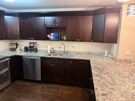 Kitchen with double ovens, modern appliances, hardwood cabinets, and hanging light fixtures