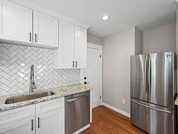 This photo shows the back entrance to the unit as well as the updated kitchen, featuring stainless steel appliances, ample cabinets, and granite countertops.