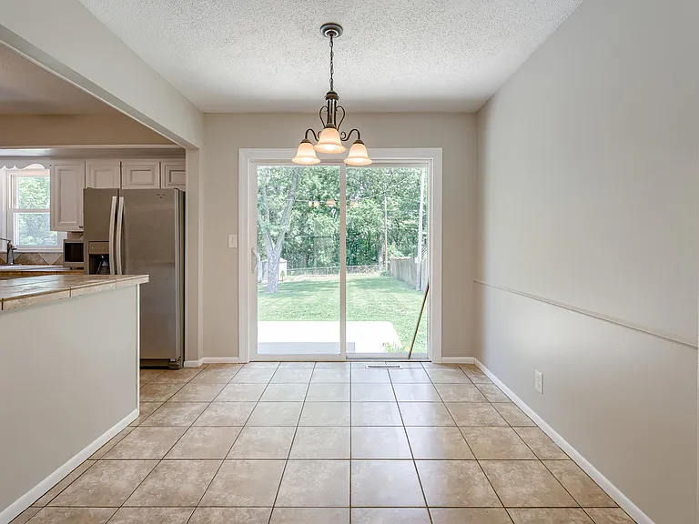 Dining room featuring nice light fixture, tile, and glass sliding doors out to the concrete patio in the fenced backyard
