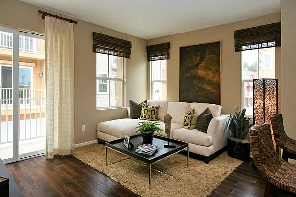 Living room with hardwood flooring, lots of windows and sliding glass doors to balcony at Serenata Townhomes in San Diego, California.