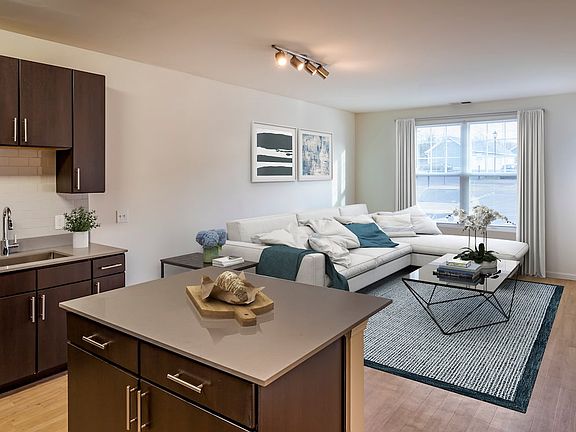 Newly renovated apartment homes feature kitchens with espresso cabinetry, grey quartz countertops, stainless steel appliances, grey tile backsplash, and hard surface flooring