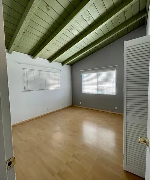 Spacious master bedroom with open beam ceiling and wood floor