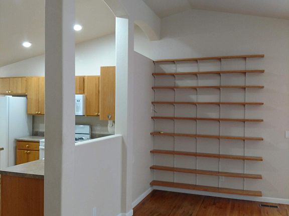 Living room has large shelving unit and a pass through window into kitchen