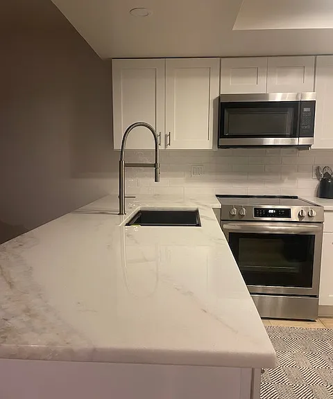 Newly renovated kitchen: white shaker cabinets, marble counter tops, stainless steel appliances with convection oven, microwave, side-by-side refrigerator with ice and water dispenser, and dishwasher.
