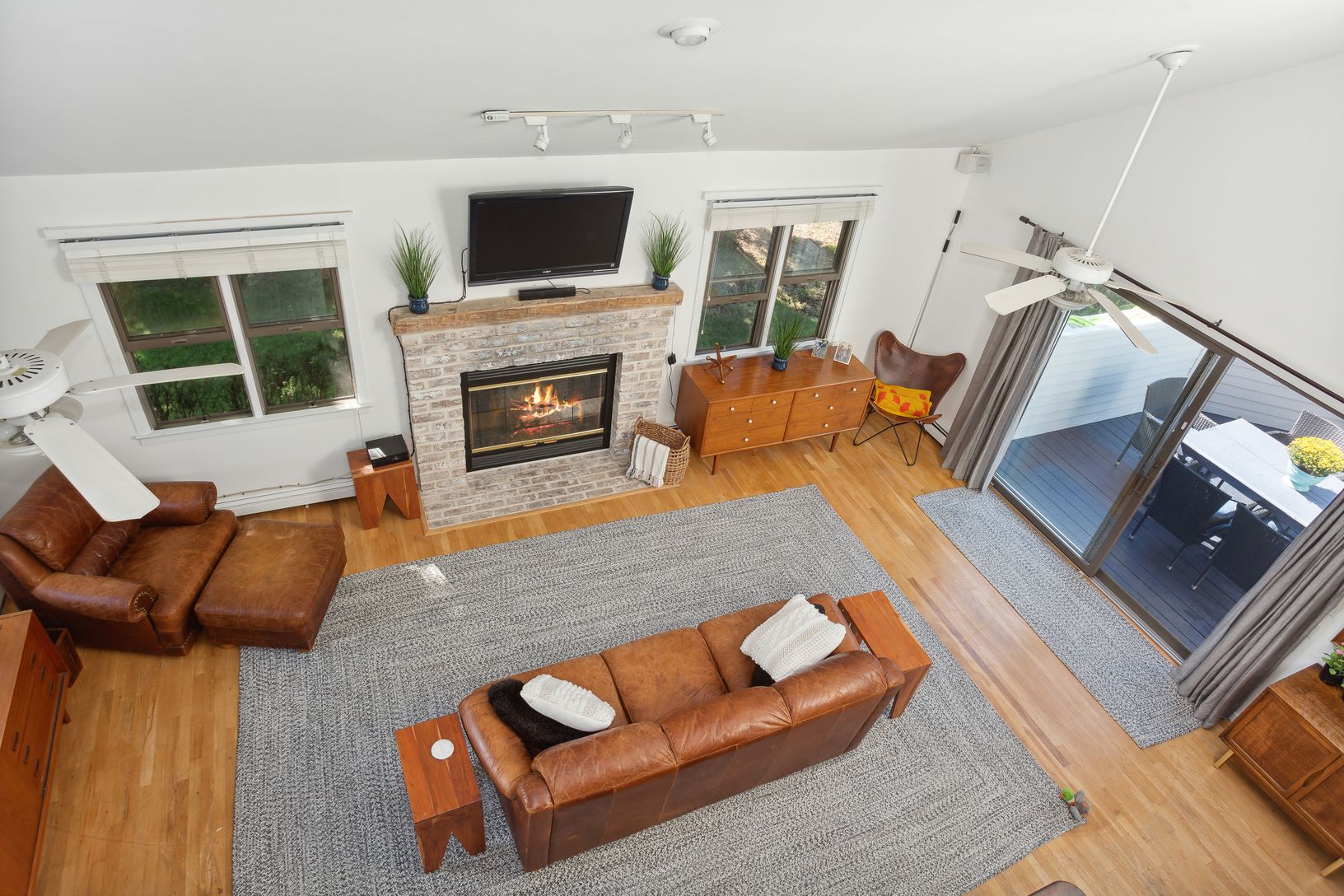  Overhead view of living room with fireplace & sliders to pool deck, grilling area