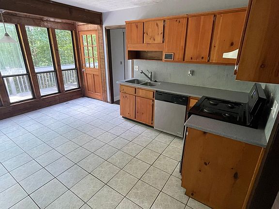 Kitchen has windows looking out over deck, backyard and into woods