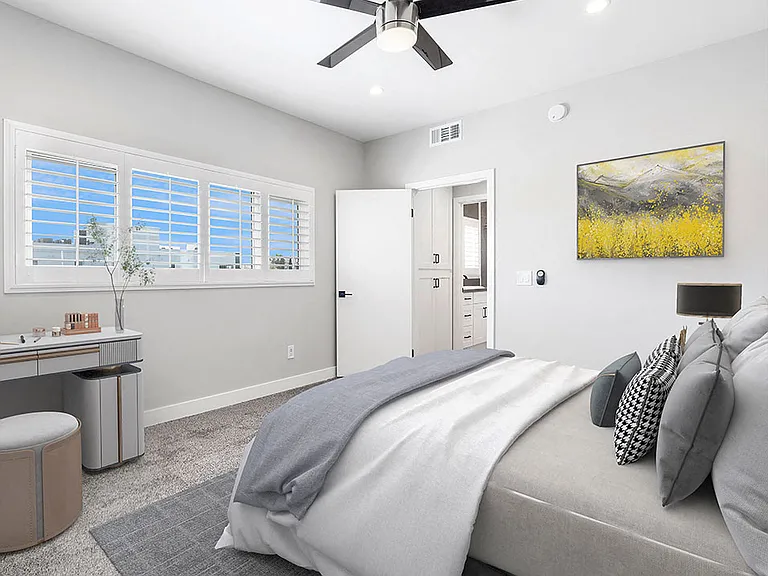 Carpeted bedroom with ceiling fan and large windows for natural light.