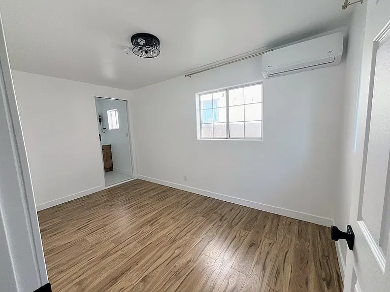 View of bedroom from the bedroom door. 
Door to bathroom at the left wall.
AC unit on the right upper wall.