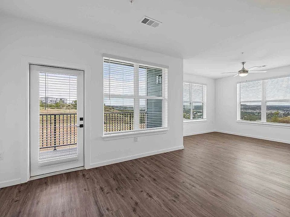 Windows on two walls plus a balcony door bring light into the C1 living and dining area from three directions. Window count and exposure vary by home.
