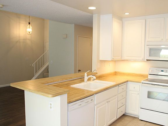 Kitchen counter offers plenty of space for entertaining guests on opposite side, dual sink, bright white cabinets, and new appliances.
